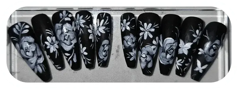 Black nails with white flowers I designed and hand-painted. Read about my nail art