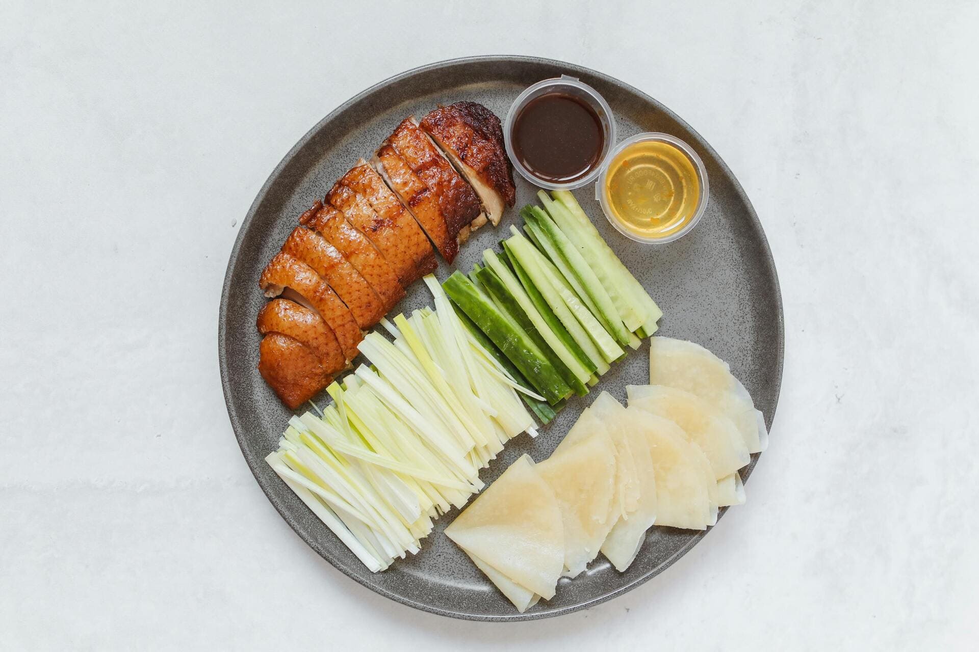 Peking Duck: Crispy, shiny duck skin wrapped in thin pancakes with cucumber, scallions, and sweet bean sauce