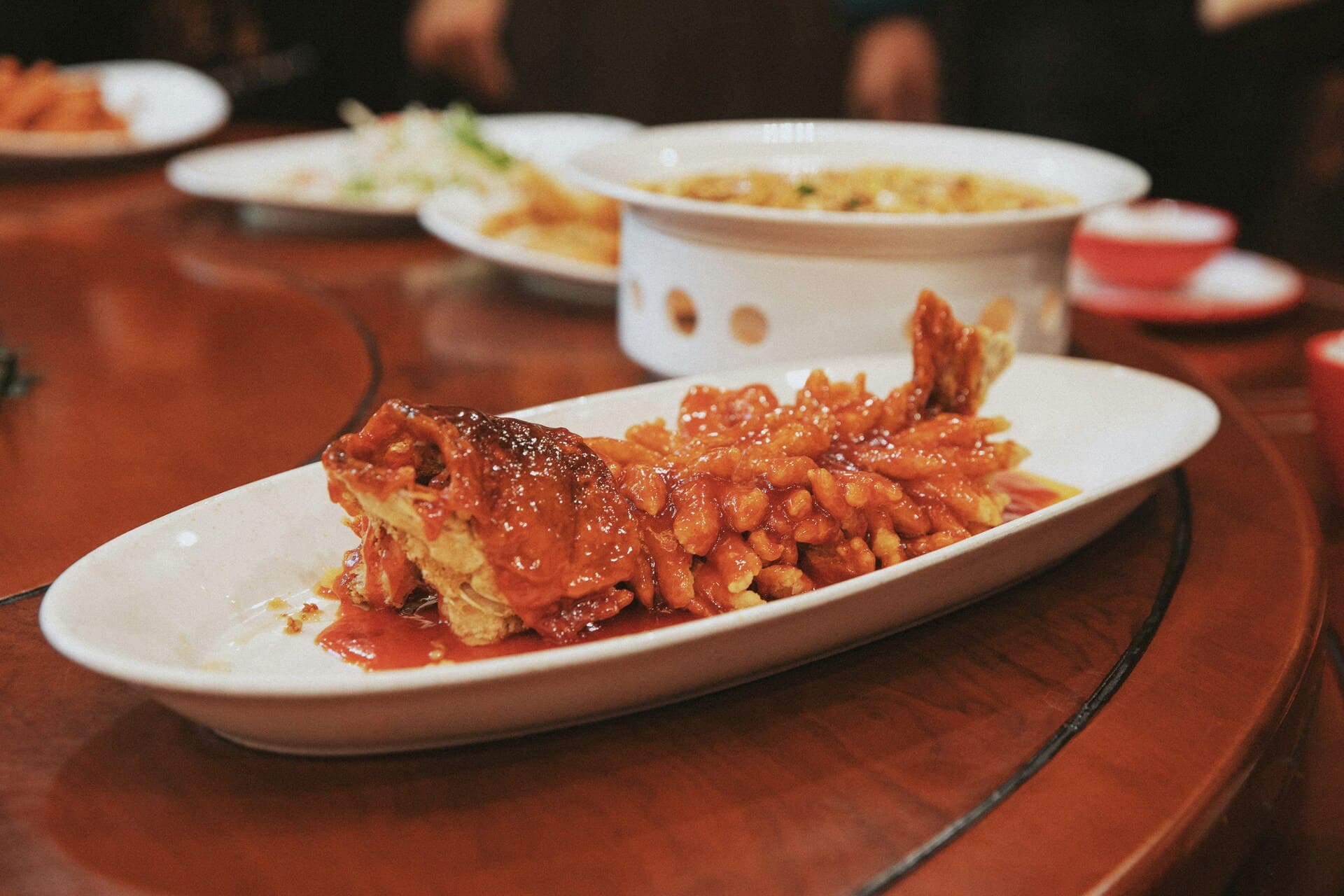 Squirrel Fish: Deep-fried whole fish with a crispy golden exterior, drizzled in a glossy red sweet and sour sauce